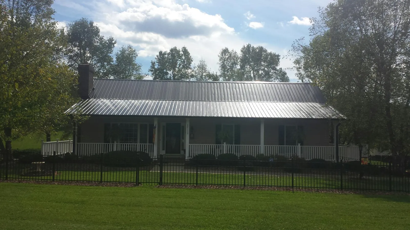 Gray metal roof on a brick ranch with a full width front porch — Gutter Guard Installation work by our crew in Levasy