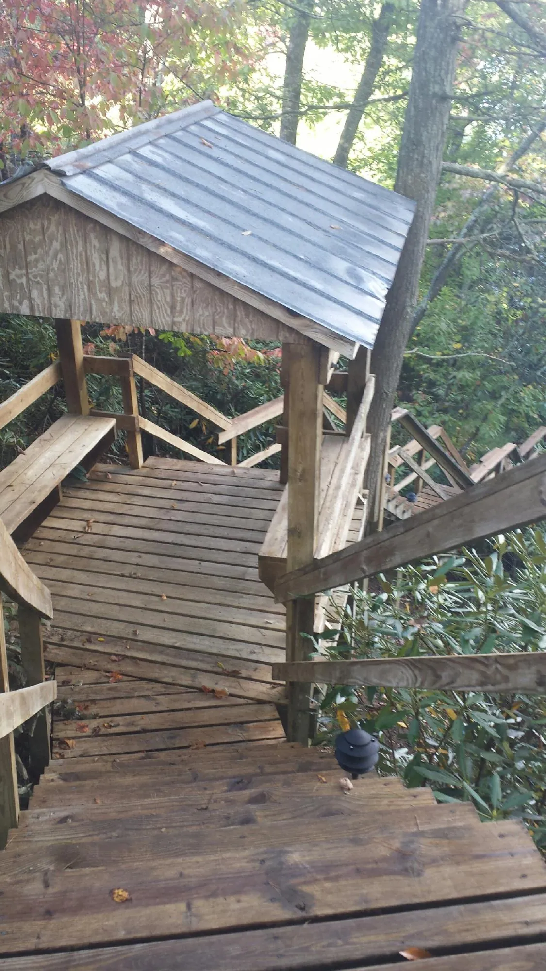 Metal roofed shelter over wooden steps on a wooded walkway — Skylight Repair & Installation work by our crew in Levasy