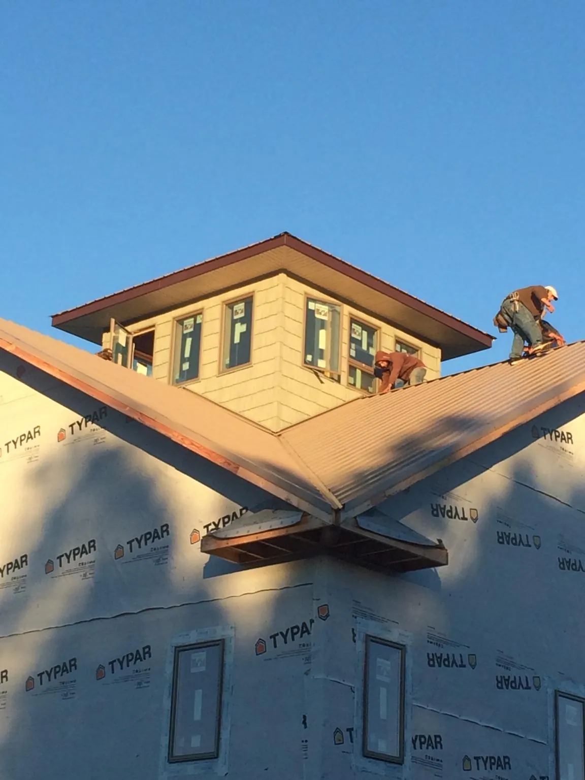 Roofers working around a rooftop cupola on a new metal roof at sunset — Roof Waterproofing in Levasy by Roofing Brothers
